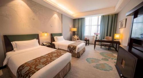 a hotel room with two beds and a desk at Jin Jiang Nanjing Hotel in Nanjing