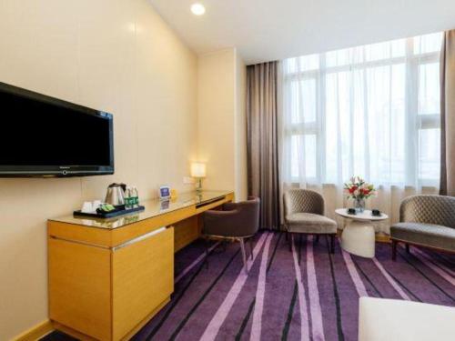 a hotel room with a flat screen tv on the wall at The Bauhinia in Shenzhen