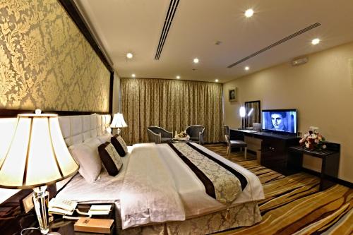 Schlafzimmer mit einem Bett, einem Schreibtisch und einem TV in der Unterkunft Garden Plaza Hotel in Al Hofuf