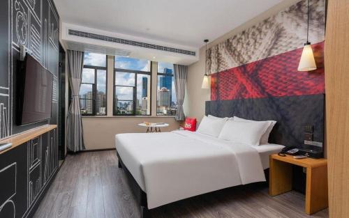 ein Schlafzimmer mit einem großen weißen Bett und einem Fernseher in der Unterkunft ibis Kunming Beijing Rd in Kunming
