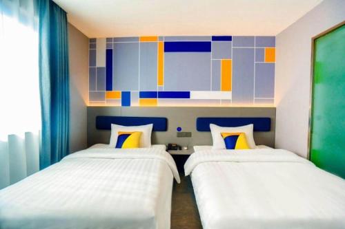 two beds in a room with a colorful wall at 7 Days Inn Xi'an Railway Station in Xi'an