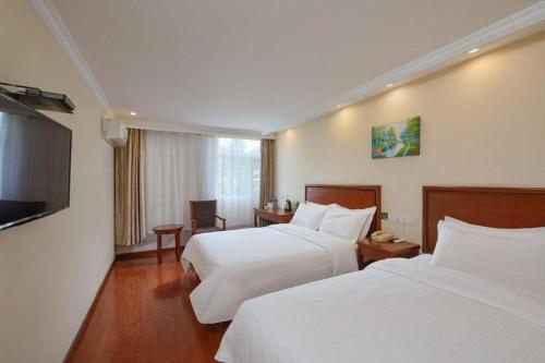 a hotel room with two beds and a flat screen tv at GreenTree Inn Nanjing Forestry University National Exhibition Center Express Hotel in Nanjing