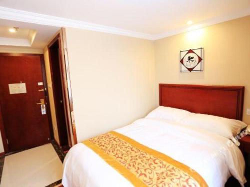a bedroom with a bed with a wooden head board at GreenTree Inn Nanjing Forestry University National Exhibition Center Express Hotel in Nanjing