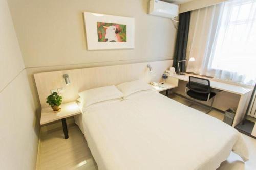 a hotel room with a white bed and a desk at Jinjiang Inn Hohhot Dazhao Hospital Metro Station in Hohhot
