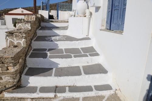 a stone walkway next to a building with a blue door at Aura Loutra Kythnos in Kithnos