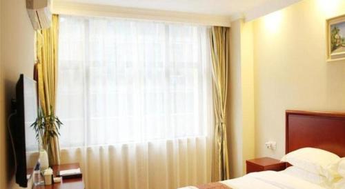 a bedroom with a bed and a large window at GreenTree Inn Fuyang Yijing International North Business in Fuyang