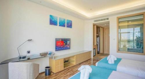 a bedroom with a blue bed and a desk at Beluga Sanya Discovery Ocean World in Shangsimacun