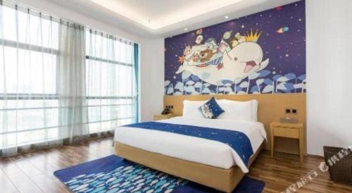 a bedroom with a large bed with a painting on the wall at Beluga Sanya Discovery Ocean World in Shangsimacun