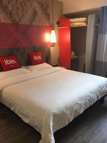 a large white bed with red pillows on it at ibis Shenyang north station in Shenyang