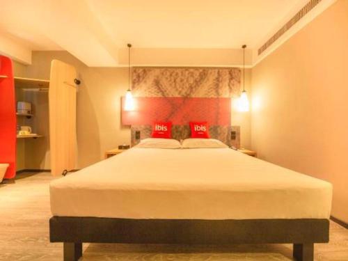 a bedroom with a large bed with red pillows at ibis Shenyang north station in Shenyang