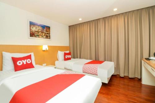 two beds in a hotel room with red and white pillows at OYO 225 Premier Place Bangkok in Bangkok