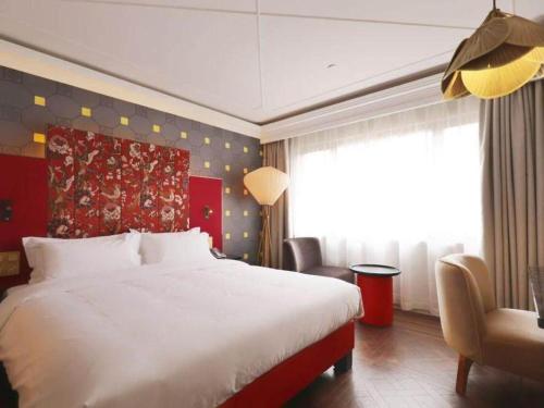 a bedroom with a large white bed and a chair at Jinjiang Metropolo Shanghai Xujiahui Nanhuating Hotel in Shanghai