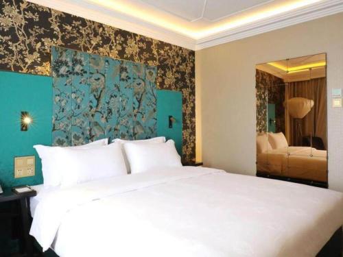 a bedroom with a white bed and a blue wall at Jinjiang Metropolo Shanghai Xujiahui Nanhuating Hotel in Shanghai