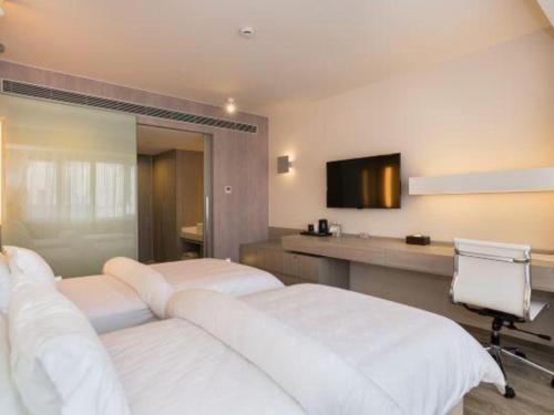 a hotel room with two beds and a television at Jinjiang Metropolo Shanghai Xujiahui Nanhuating Hotel in Shanghai