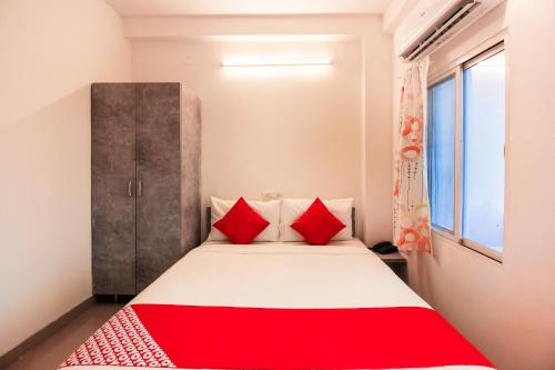 a bedroom with a bed with red pillows at Hotel O D' Jade in Hyderabad