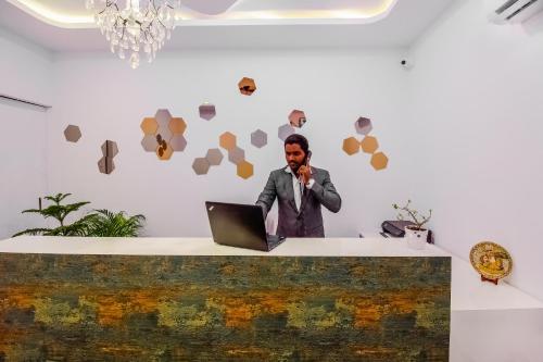 a man talking on a phone in front of a laptop at Hotel O D' Jade in Hyderabad
