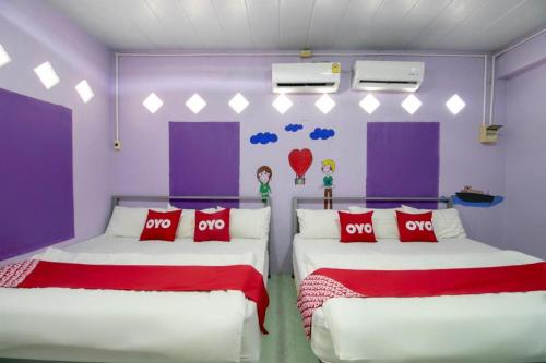 two beds in a room with purple walls at OYO 931 Sor Chareanpanit in Pattaya Central