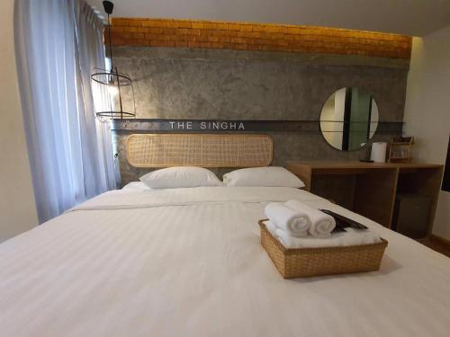 a bedroom with a white bed with towels on it at The Singha Hotel - Korat in Nakhon Ratchasima
