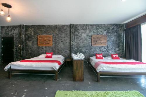 a bedroom with two beds with red pillows on them at OYO 75374 Baan Rak Mai in Kanchanaburi