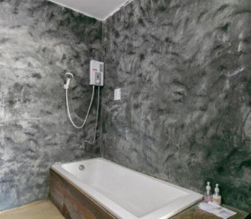 a bathroom with a bath tub and a stone wall at OYO 75374 Baan Rak Mai in Kanchanaburi