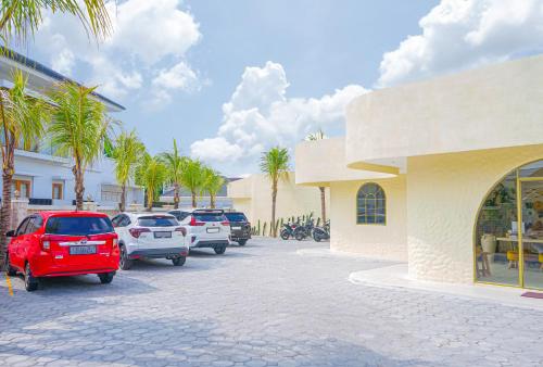 a parking lot with parked cars and palm trees at La Dorada by Bohemian Jogja Villas in Jetis