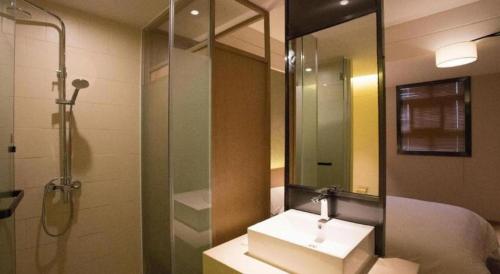 a bathroom with a sink and a shower and a mirror at V8 Ziyuangang Hotel in Guangzhou