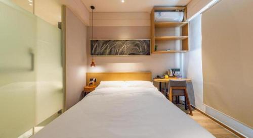 a bedroom with a large white bed and a desk at V8 Ziyuangang Hotel in Guangzhou