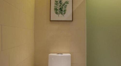 a toilet in a bathroom with a picture on the wall at V8 Ziyuangang Hotel in Guangzhou