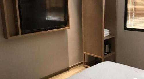 a bedroom with a bed and a large flat screen tv at V8 Ziyuangang Hotel in Guangzhou