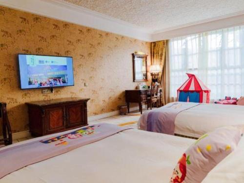 a hotel room with two beds and a flat screen tv at Hangzhou The First World Hotel in Hangzhou