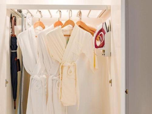 a closet with white clothes hanging on a rack at Hangzhou The First World Hotel in Hangzhou
