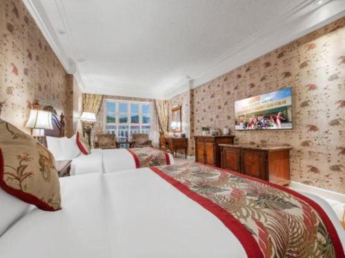a hotel room with two beds and a flat screen tv at Hangzhou The First World Hotel in Hangzhou