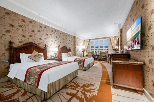 a hotel room with two beds and a television at Hangzhou The First World Hotel in Hangzhou