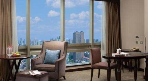 a room with two chairs and a large window at Changsha Huatian Hotel in Changsha