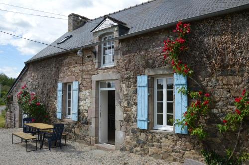 Ce cottage en pierre dispose d'une table et de chaises. dans l'établissement Maison typique avec jardin, 5km de la plage, à Plévenon