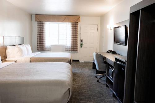 a hotel room with two beds and a flat screen tv at Quality Inn & Suites Lathrop in Lathrop