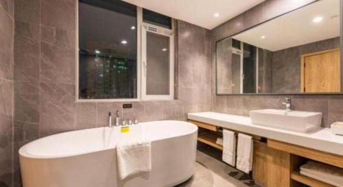 a bathroom with a large tub and two sinks at New Beacon Sunyee SPA Hotel in Wuhan
