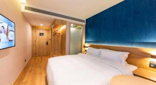 a bedroom with a large white bed with a blue wall at New Beacon Sunyee SPA Hotel in Wuhan