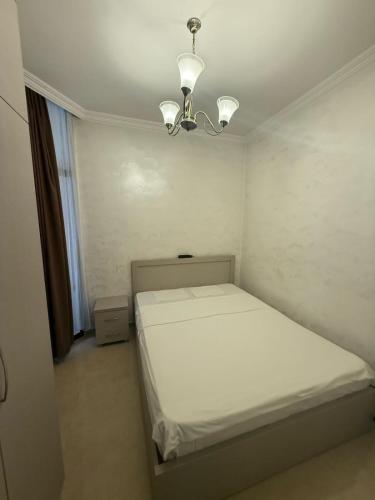 a small bedroom with a white bed and a chandelier at Sweet Batumi GEO in Itʼkhvisi