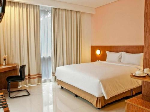 a hotel room with a large bed and a window at Pomelotel Patra Kuningan Jakarta in Jakarta