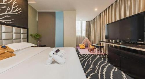 a bedroom with a large white bed and a flat screen tv at Kunming Long Way Hotel in Kunming