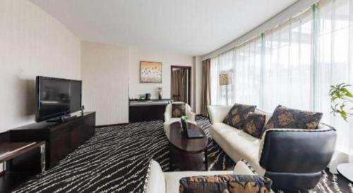 a living room with a couch and a television at Kunming Long Way Hotel in Kunming