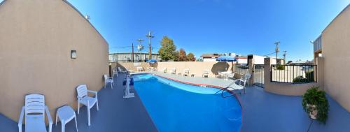 a swimming pool with white chairs and tables and a pool at Americas Best Value Inn - Brookhaven in Brookhaven
