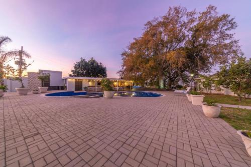 a brick courtyard with a pool and trees and a building at Room 6 - LEO Sky Guest House in Simondium