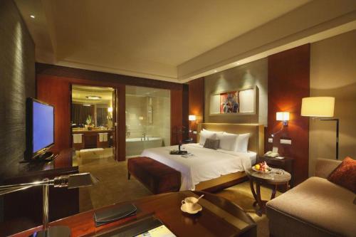 a hotel room with a bed and a living room at Quanzhou Guest House Hotel in Quanzhou
