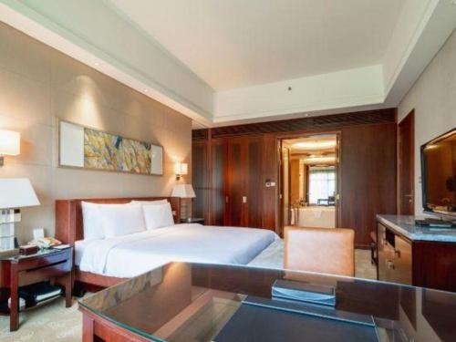 a hotel room with a bed and a television at Quanzhou Guest House Hotel in Quanzhou