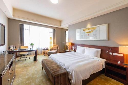 a hotel room with a large bed and a desk at Quanzhou Guest House Hotel in Quanzhou