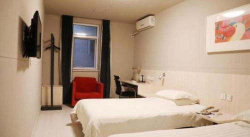 a hotel room with two beds and a red chair at Jinjiang Inn Changchun Xi An Avenue Branch in Changchun