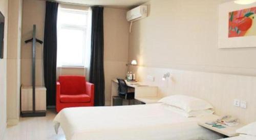 a hotel room with a bed and a red chair at Jinjiang Inn Changchun Xi An Avenue Branch in Changchun