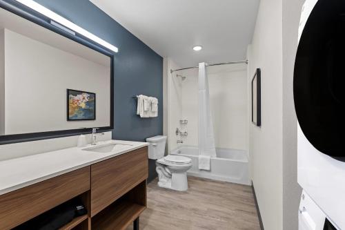 a bathroom with a white toilet and a sink at Everhome Suites Brownsville in Brownsville